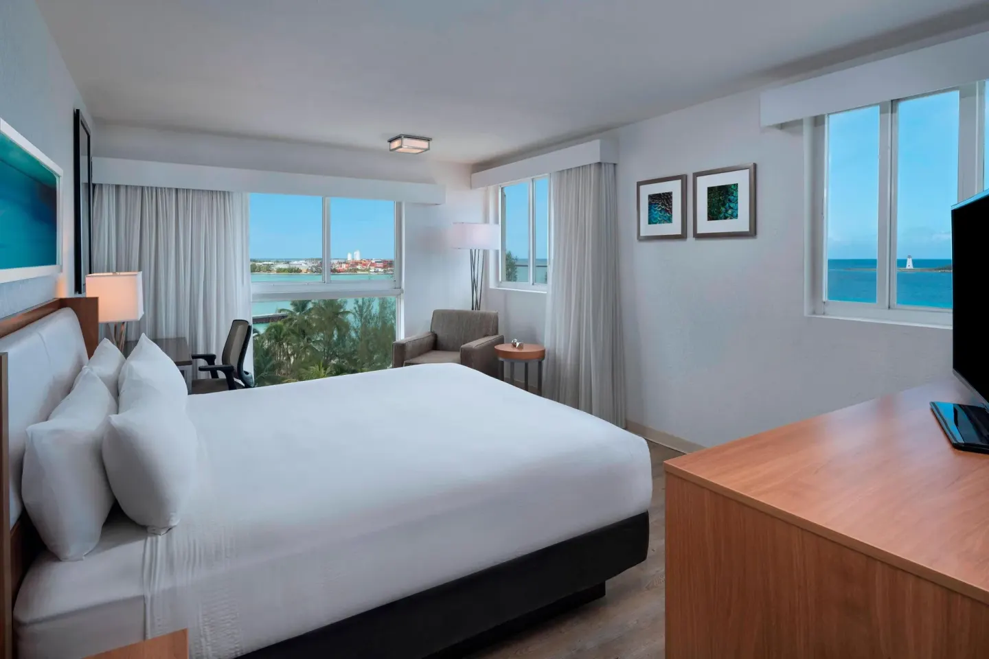 Corner guest room with king bed and ocean-facing windows at Courtyard Nassau Downtown/Junkanoo Beach.