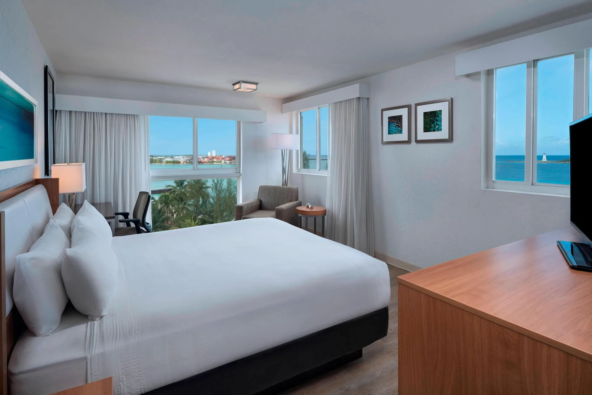 Corner guest room with king bed and ocean-facing windows at Courtyard Nassau Downtown/Junkanoo Beach.
