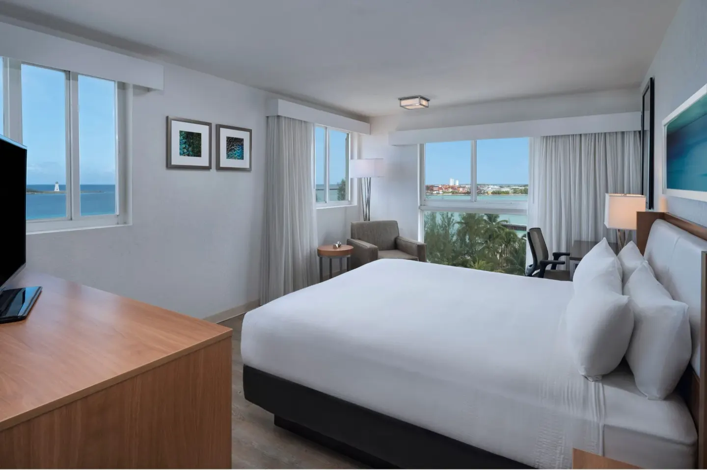 King bed corner room with desk, TV, and water views at Courtyard Nassau Downtown/Junkanoo Beach.