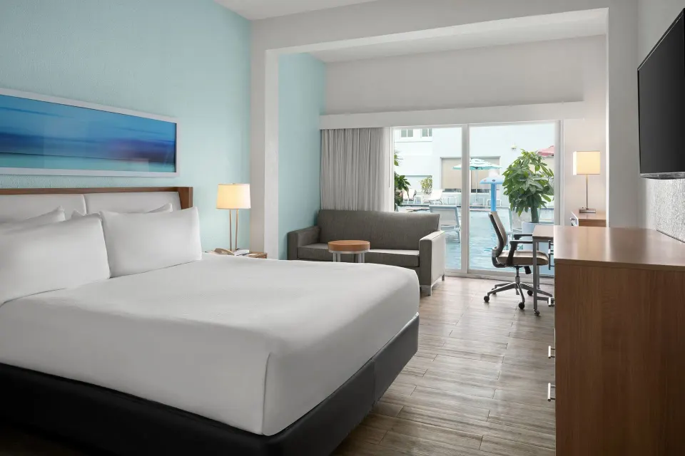 King bed and sitting area facing poolside doors at Courtyard Nassau Downtown/Junkanoo Beach.