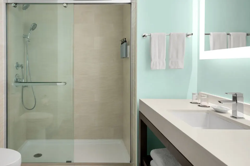 Standard room bathroom with glass shower and vanity at Courtyard Nassau Downtown/Junkanoo Beach.