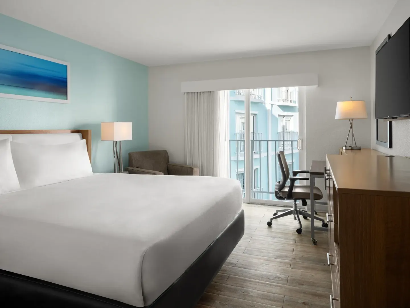 King standard room with desk, chair, and balcony door at Courtyard Nassau Downtown/Junkanoo Beach.