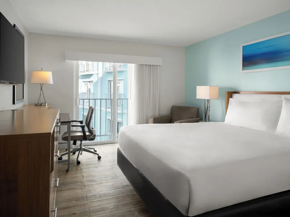 King bed, desk, and sliding glass door in a standard room at Courtyard Nassau Downtown/Junkanoo Beach.