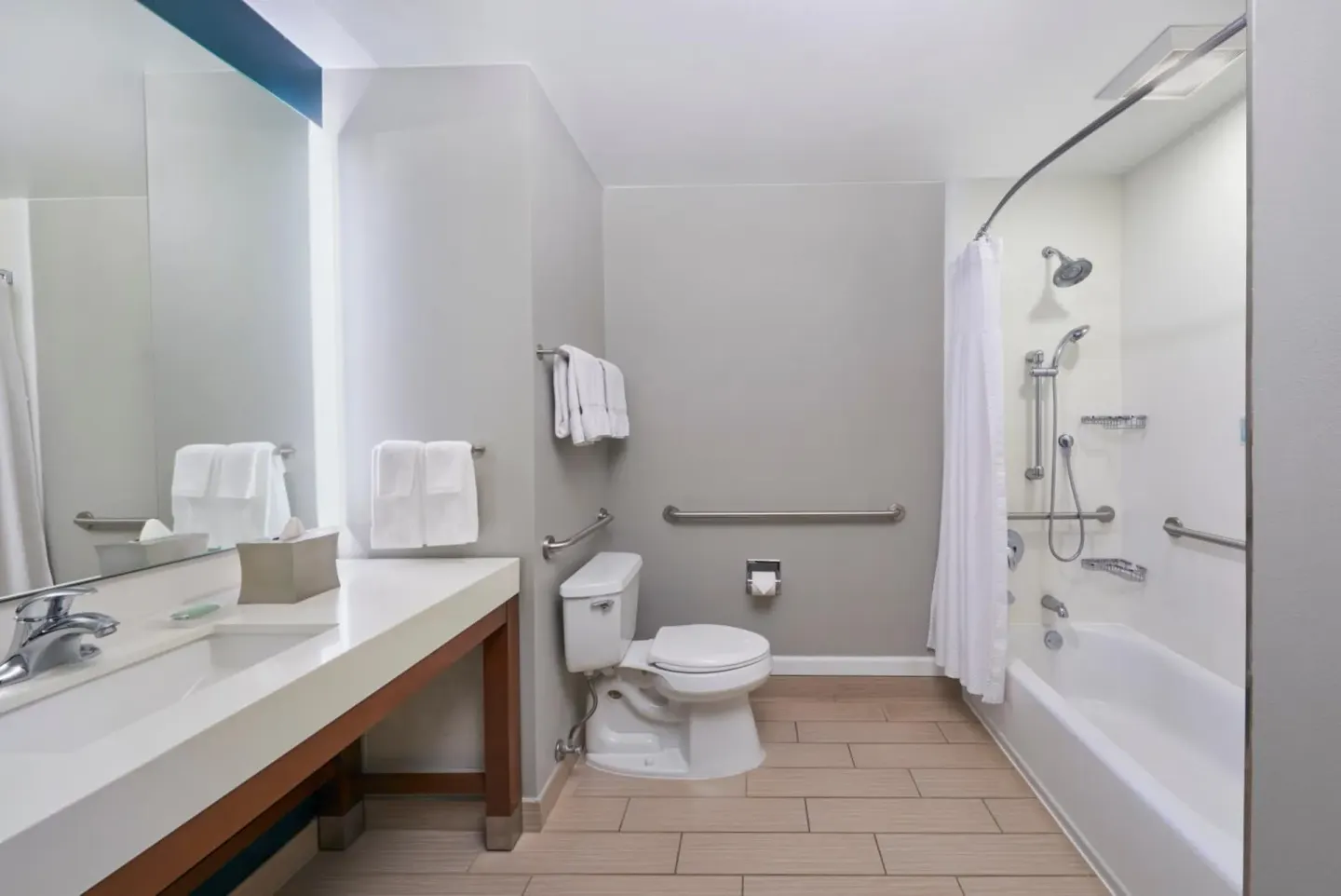 Accessible bathroom with vanity, toilet, grab bars, and tub at Courtyard Oahu North Shore.