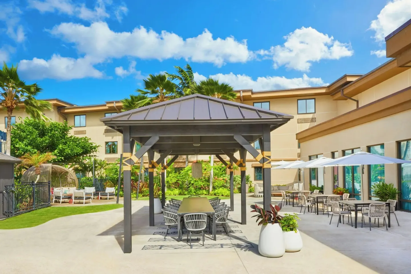 Courtyard patio with shaded tables and umbrellas at Courtyard Oahu North Shore.