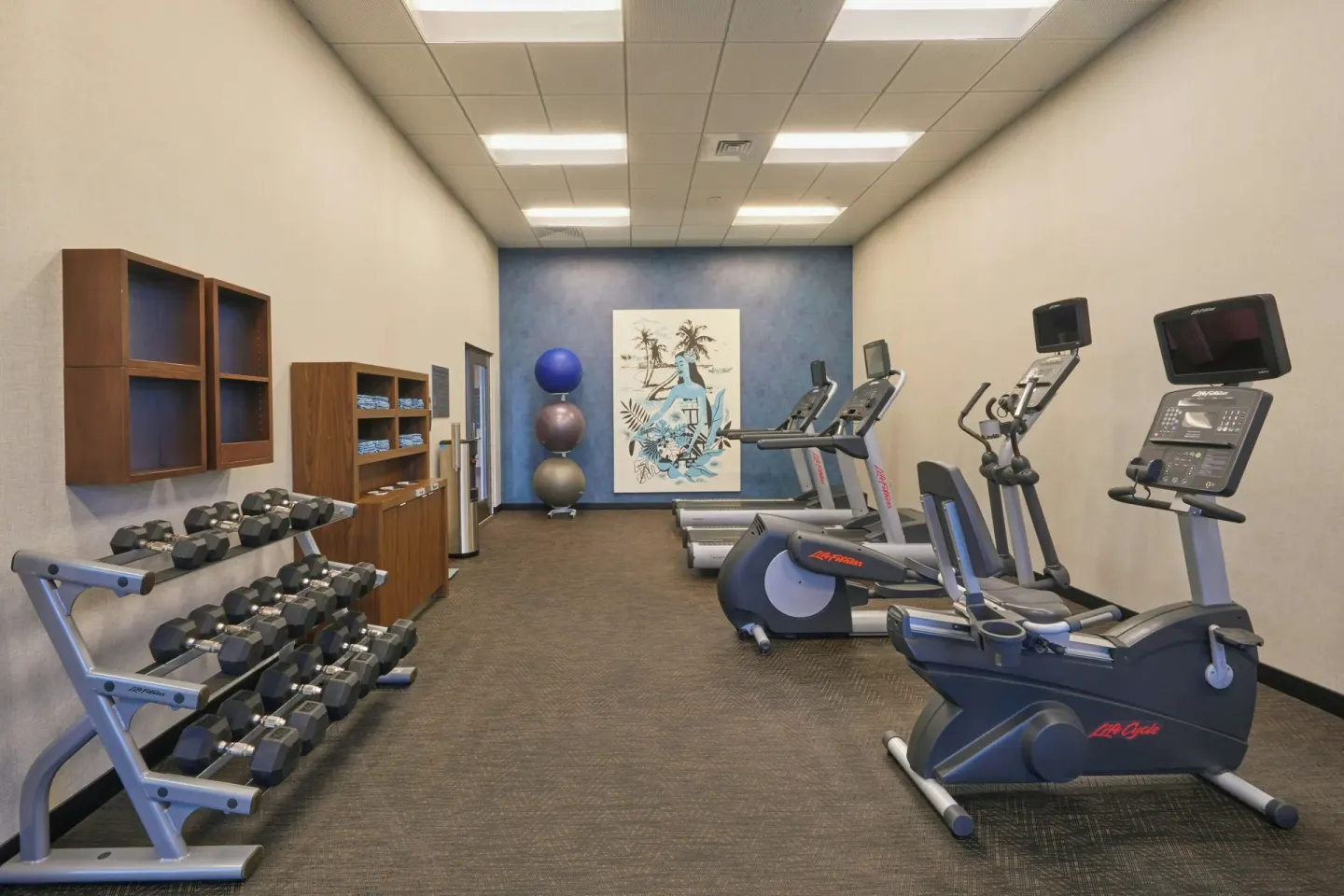 Fitness room with cardio machines and dumbbells at Courtyard Oahu North Shore.