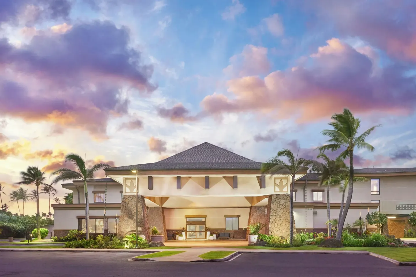 Front entrance of Courtyard Oahu North Shore under a colorful sunset sky.