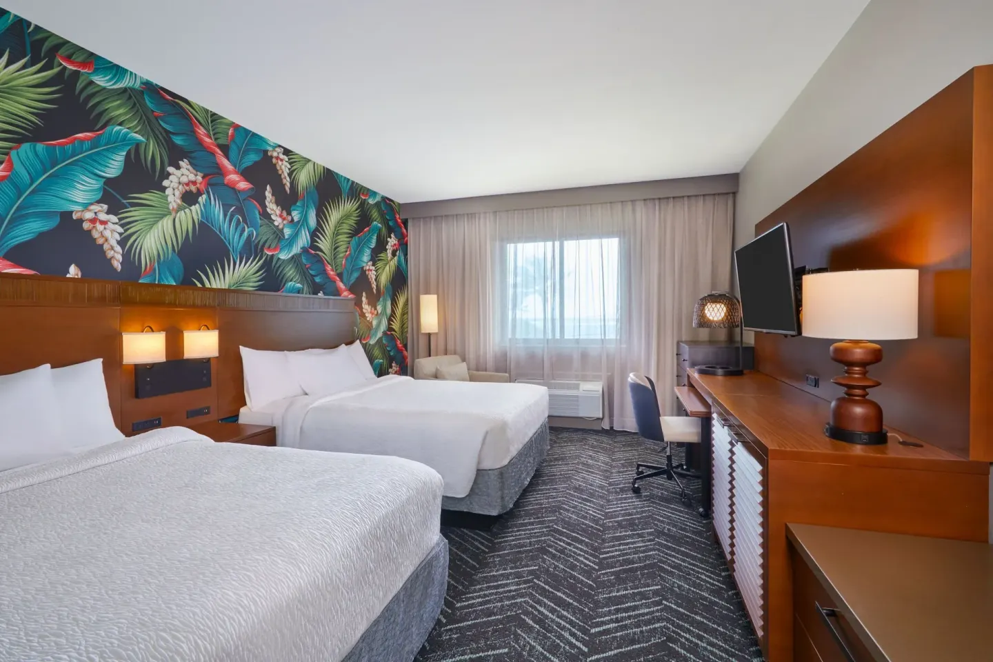 Two-bed guest room with desk and TV at Courtyard Oahu North Shore.