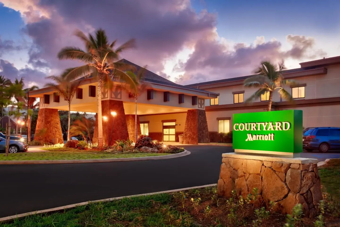 Hotel entrance and illuminated sign at dusk at Courtyard Oahu North Shore.