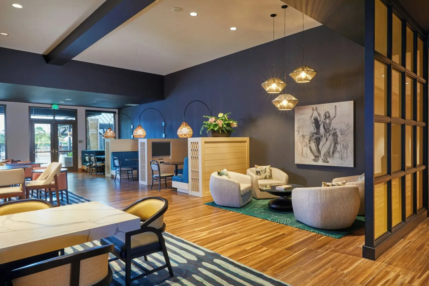Lobby seating nook with armchairs, pendant lights, and artwork at Courtyard Oahu North Shore.