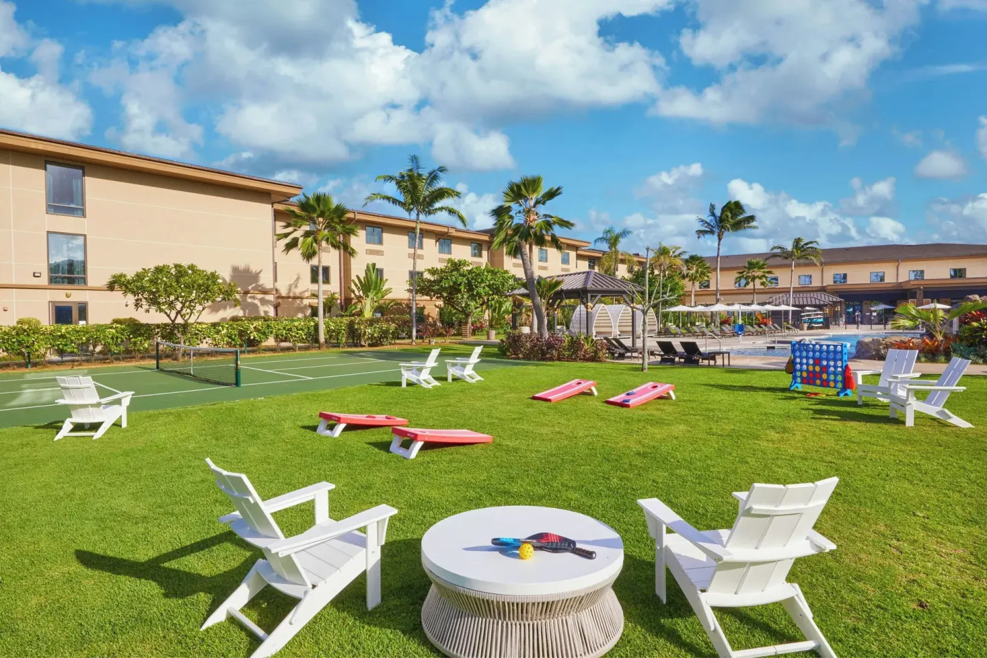 Lawn games, white chairs, and hotel buildings at Courtyard Oahu North Shore.