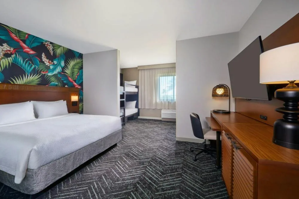 Family studio with king bed, bunk beds, desk and wall-mounted TV at Courtyard Oahu North Shore.