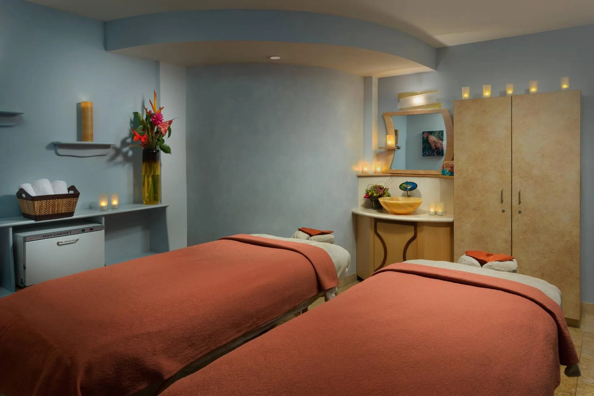 Spa treatment room with two massage tables and soft candlelight at Courtyard Waikiki Beach.