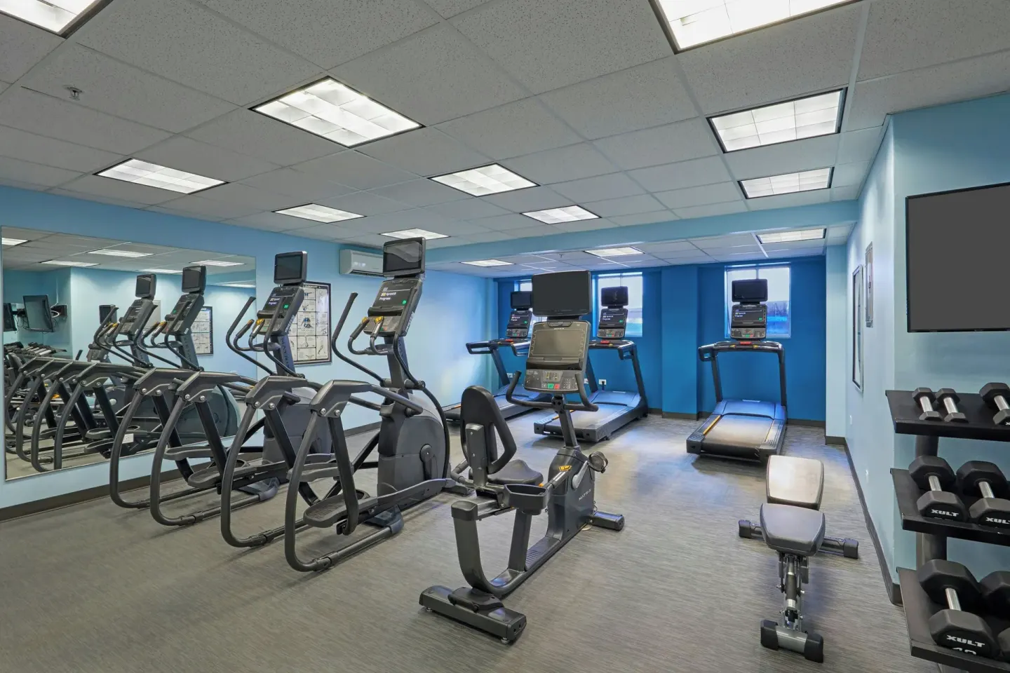 Fitness room with cardio machines and dumbbells at Courtyard Waikiki Beach.