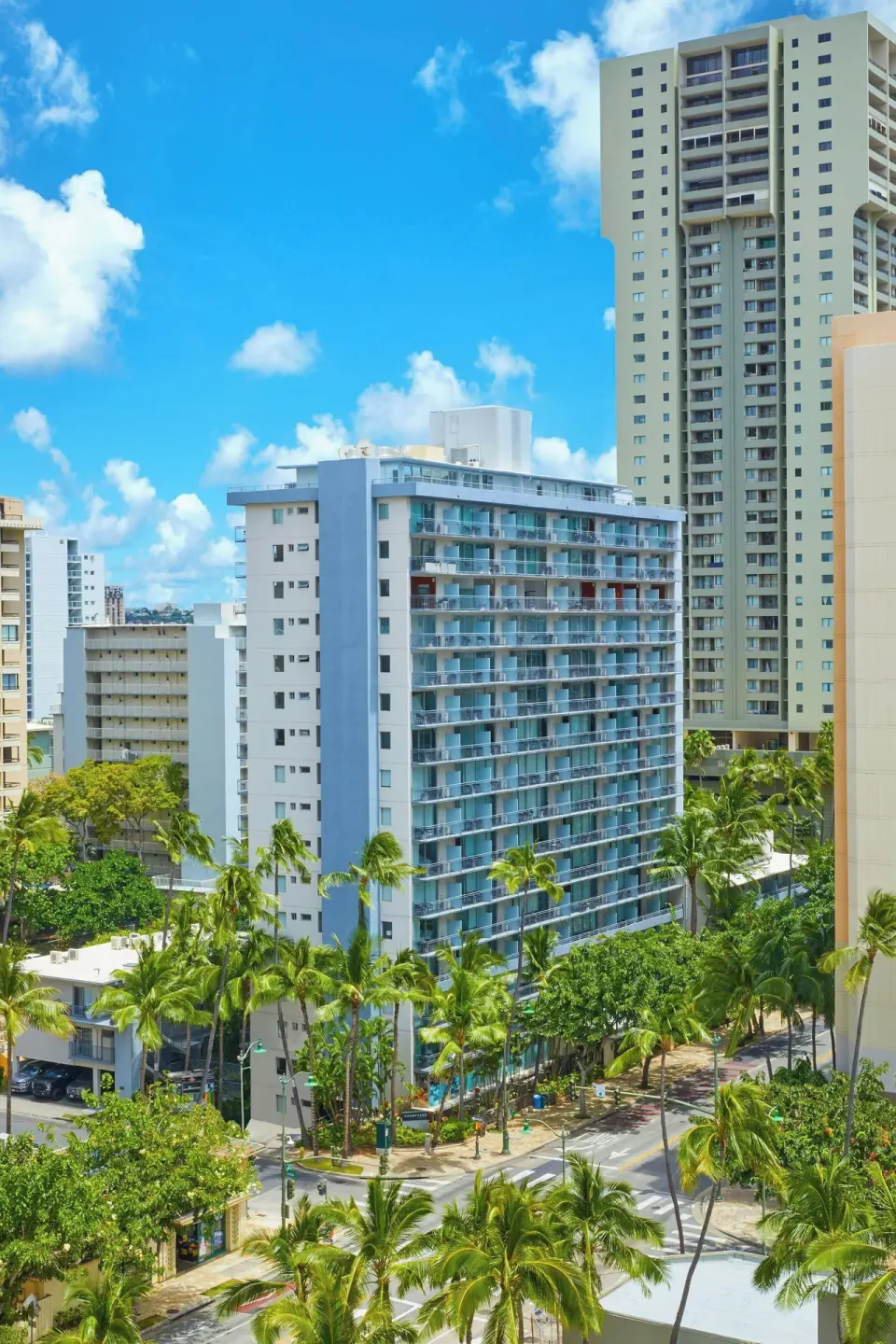 Courtyard Waikiki Beach is seen among palm trees and nearby city towers.