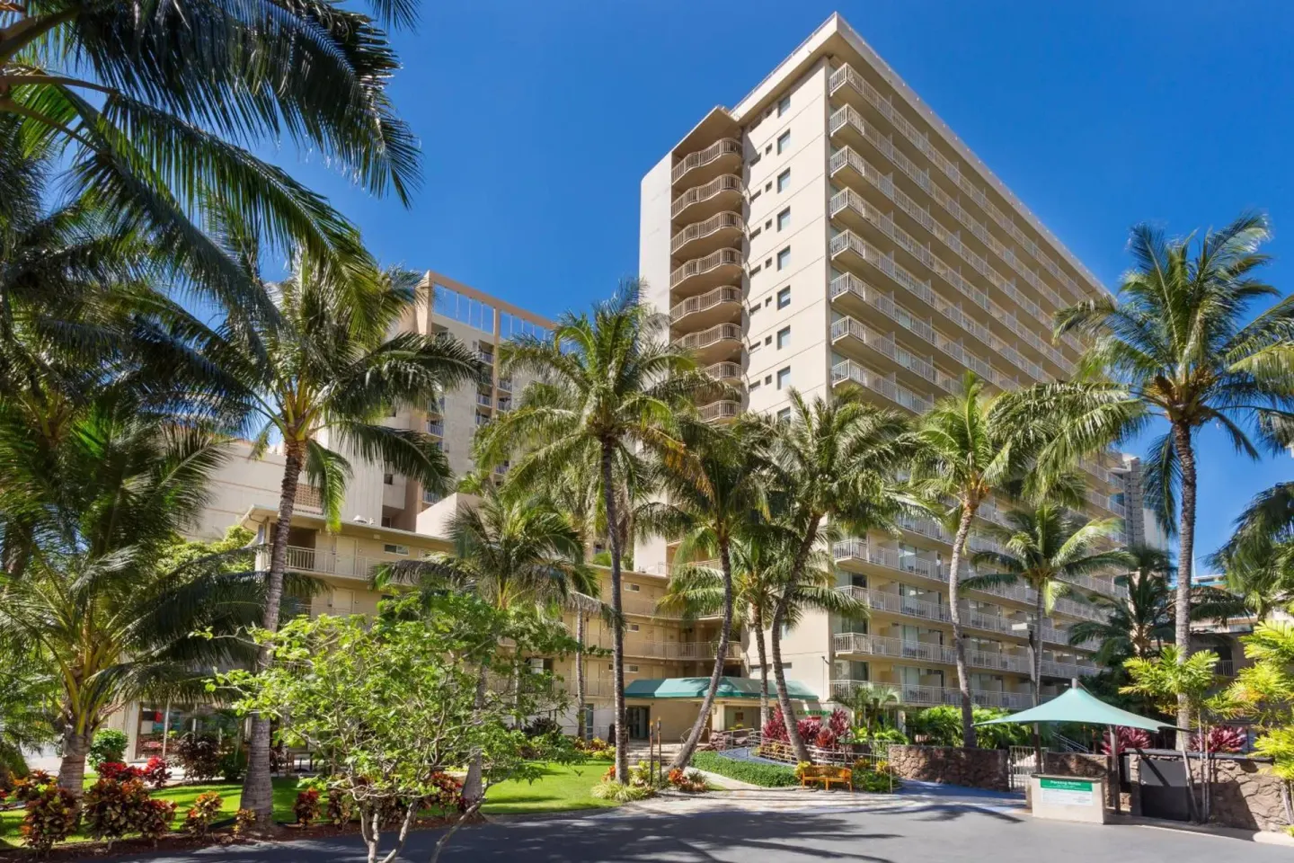 Exterior tower, balconies, palms, and driveway at Courtyard Waikiki Beach.