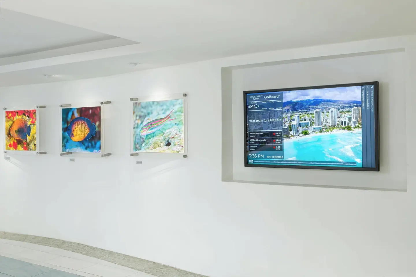 Lobby wall with colorful fish artwork and digital information screen at Courtyard Waikiki Beach.