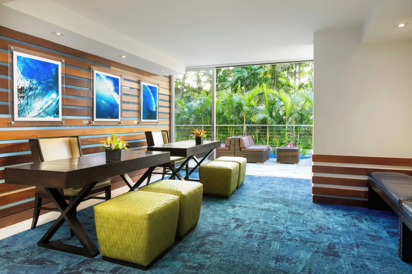 Lobby seating area with wave artwork and garden-facing windows at Courtyard Waikiki Beach.