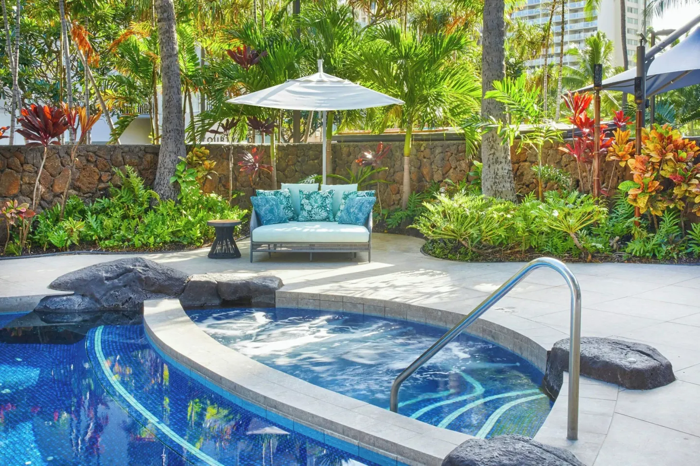 Pool and spa area with lounge seating and tropical plants at Courtyard Waikiki Beach.