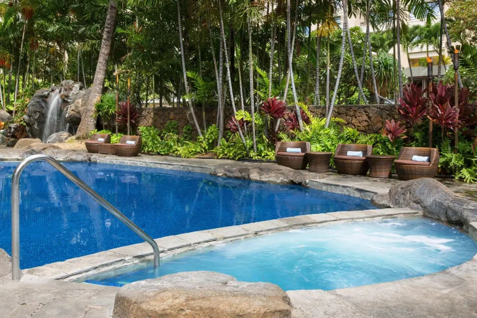 Pool and spa tub with waterfall and tropical landscaping at Courtyard Waikiki Beach.