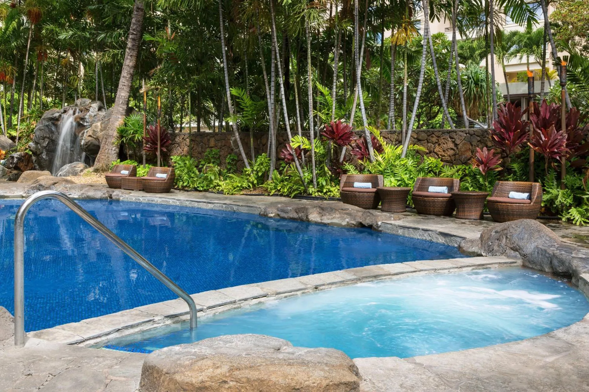 Pool and spa tub with waterfall and tropical landscaping at Courtyard Waikiki Beach.