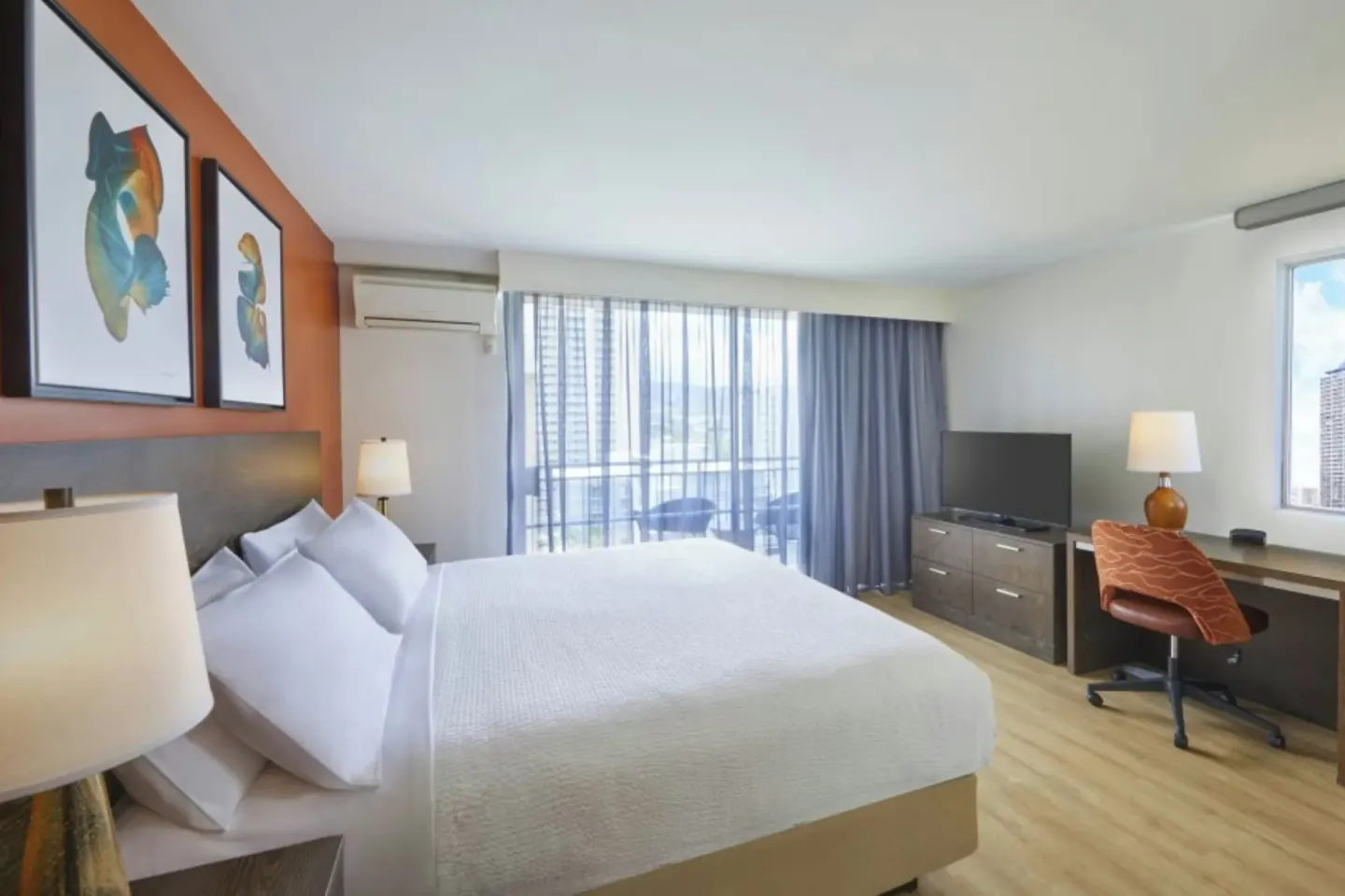 Deluxe balcony room with one bed, desk, TV, and balcony doors at Courtyard Waikiki Beach.