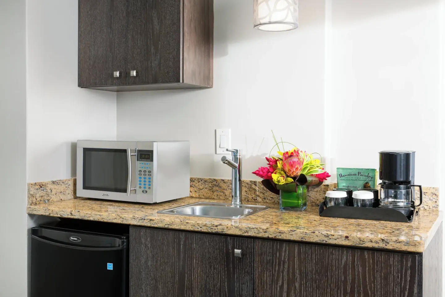 Deluxe room kitchenette with microwave, sink, mini fridge, and coffee maker at Courtyard Waikiki Beach.