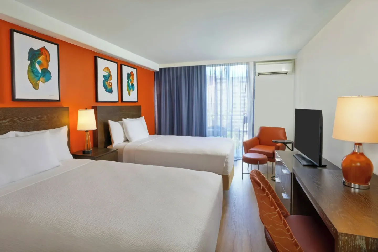 Deluxe balcony room with two beds, desk, TV, and armchair at Courtyard Waikiki Beach.