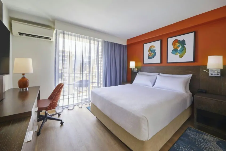 Standard Studio king bed, desk, and balcony curtains at Courtyard Waikiki Beach.