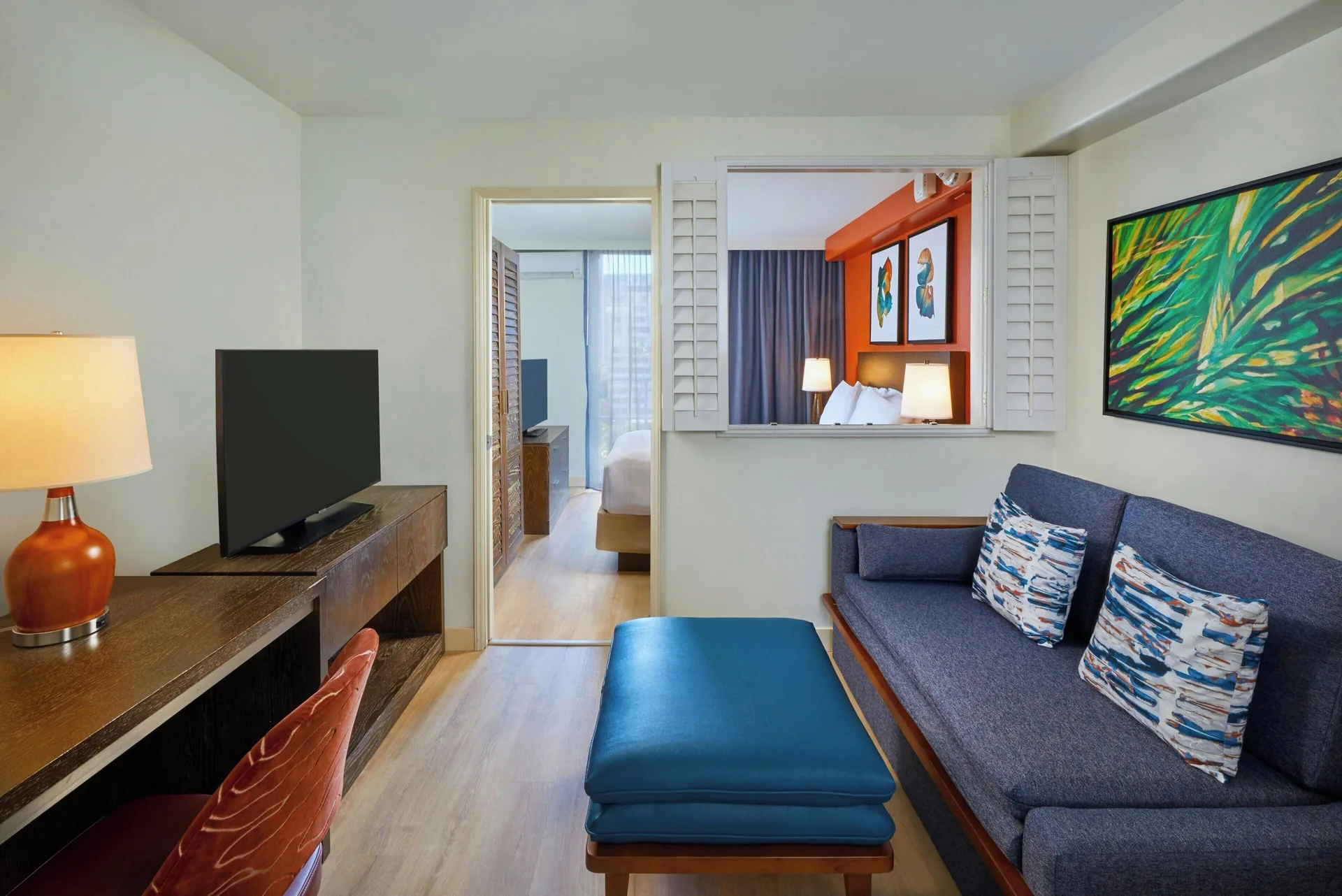 Suite living area with sofa, desk, TV, and bedroom view at Courtyard Waikiki Beach.