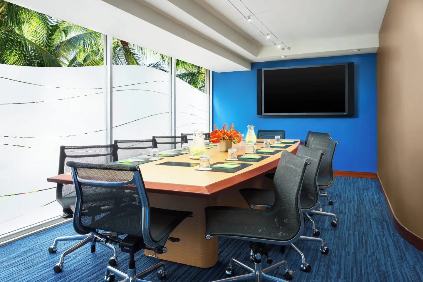 A meeting room with a long conference table and screen at Courtyard Waikiki Beach.