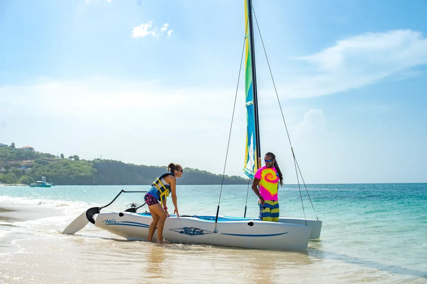Small sailboat on the beach with two people at Coyaba Beach Resort.