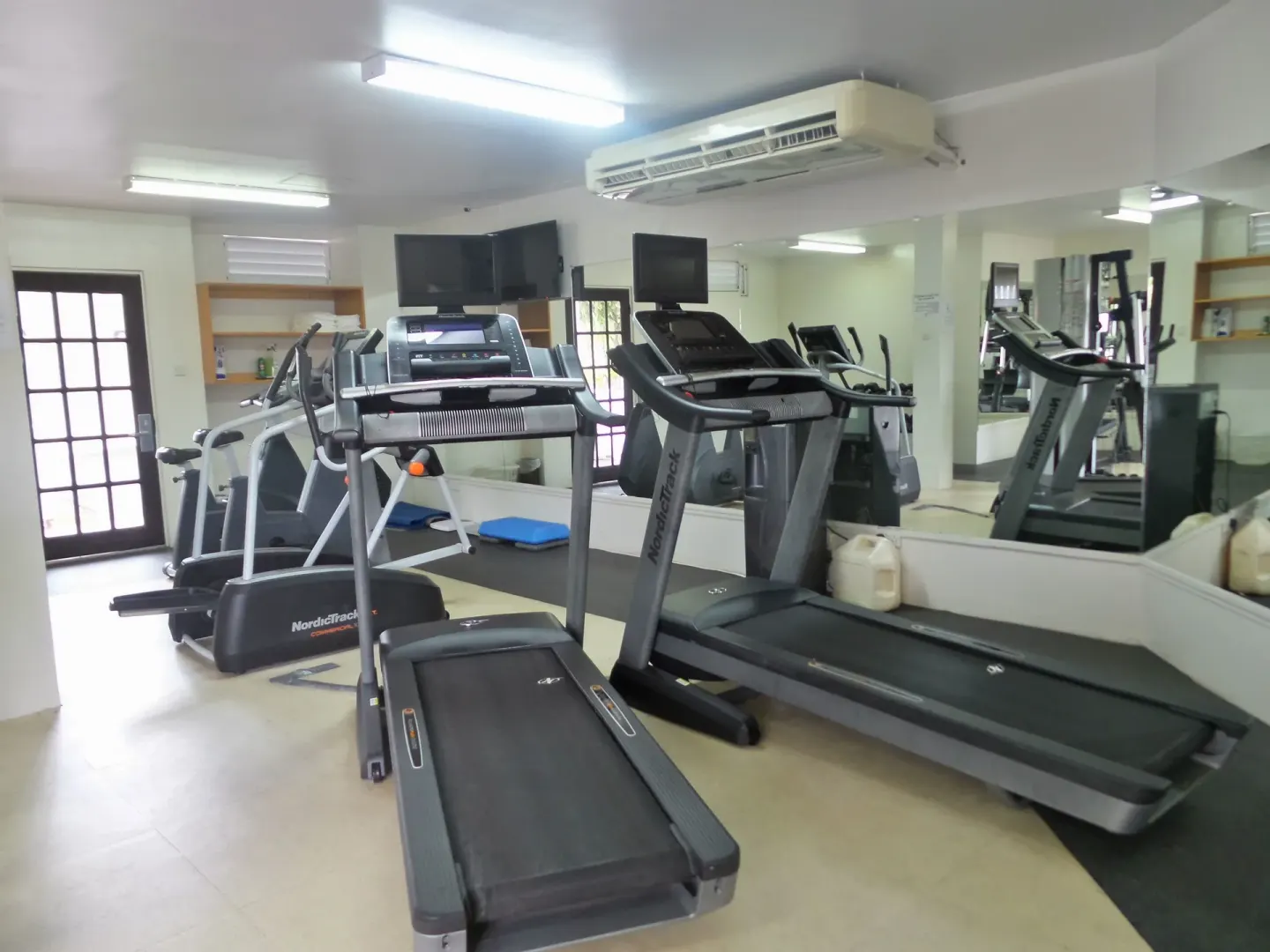 Fitness room with treadmills, mirrors, and cardio equipment at Coyaba Beach Resort.