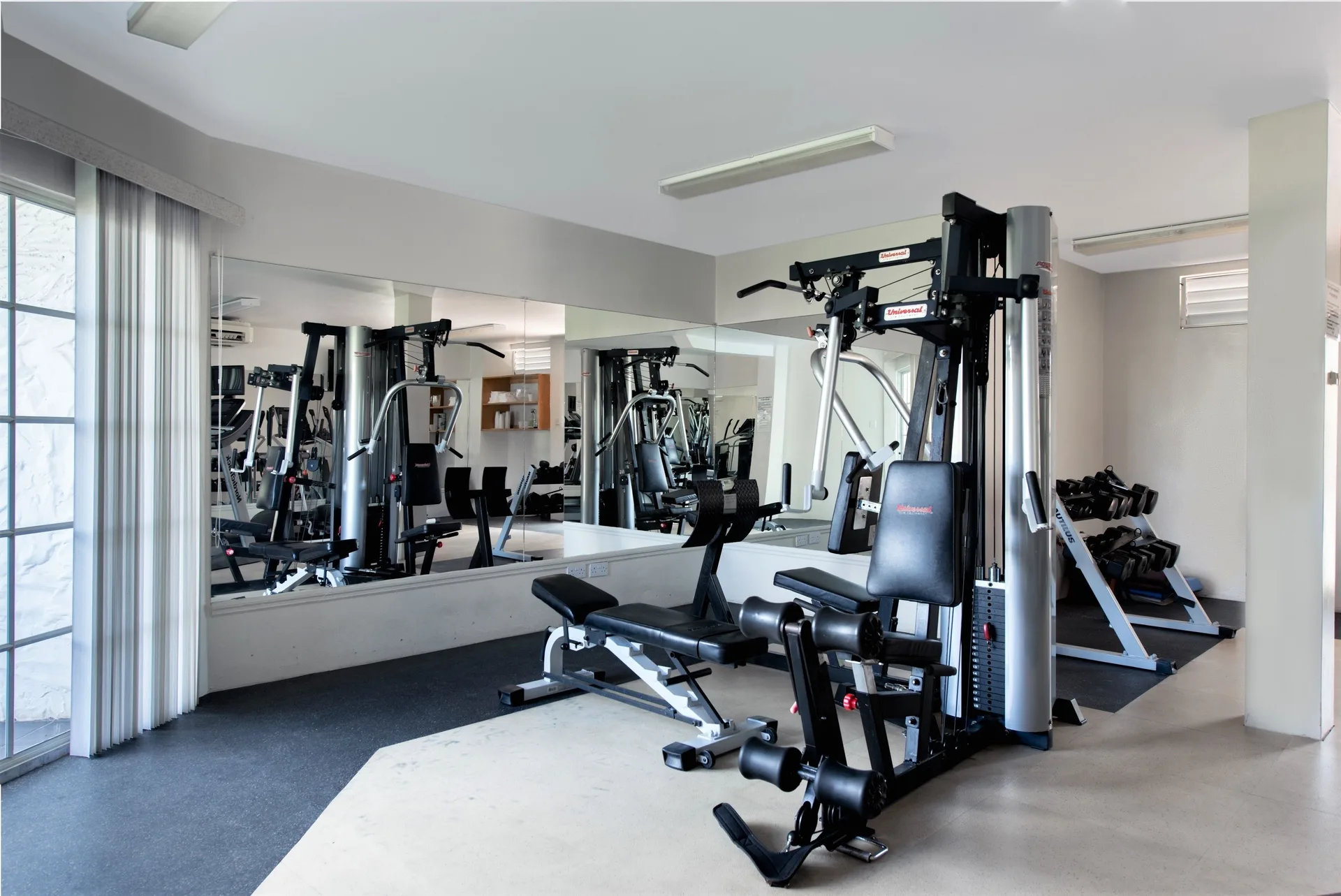 Fitness room with weight machines, dumbbells, and mirrors at Coyaba Beach Resort.