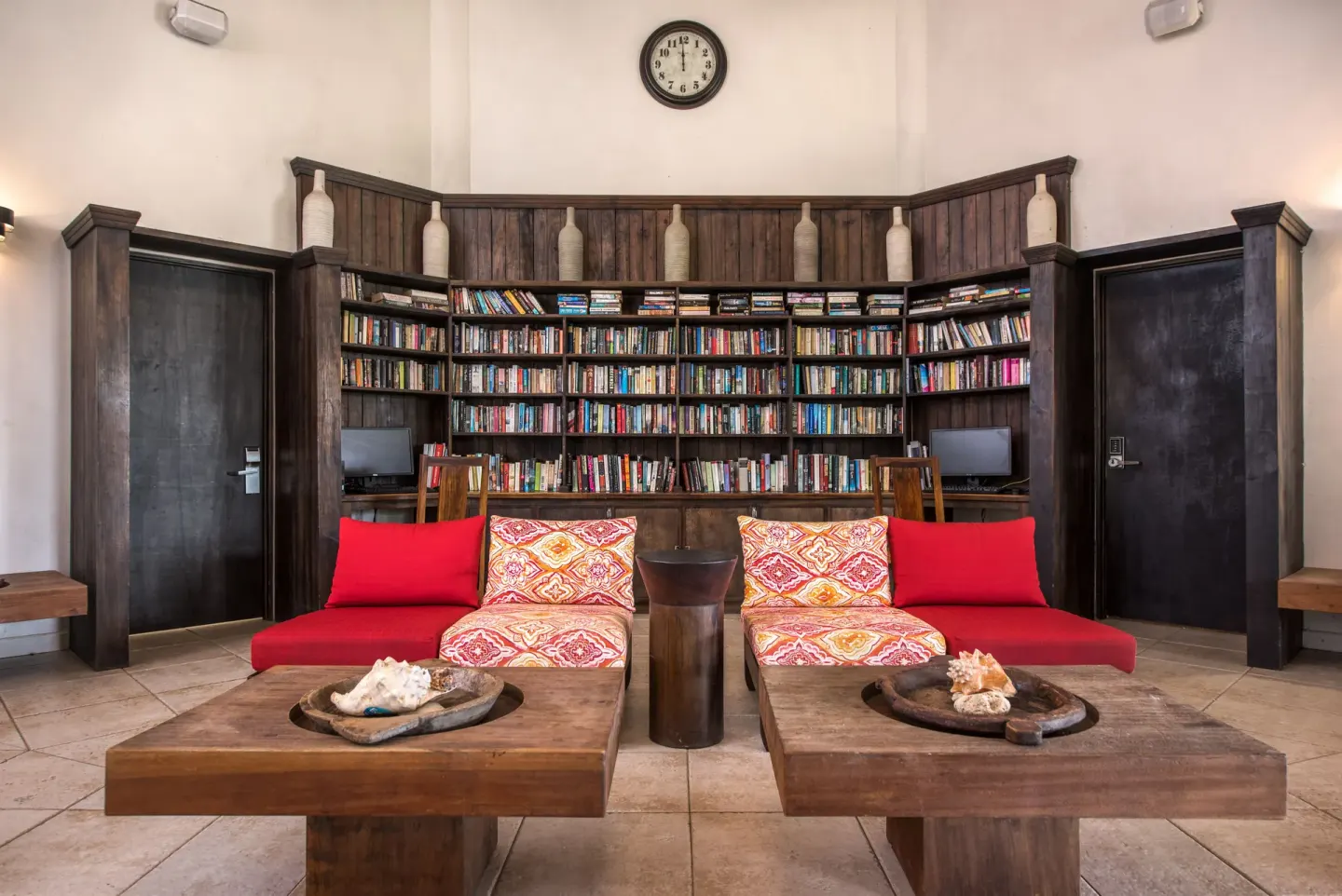 Lobby library seating with bookshelves, red sofas and wooden tables at Coyaba Beach Resort.