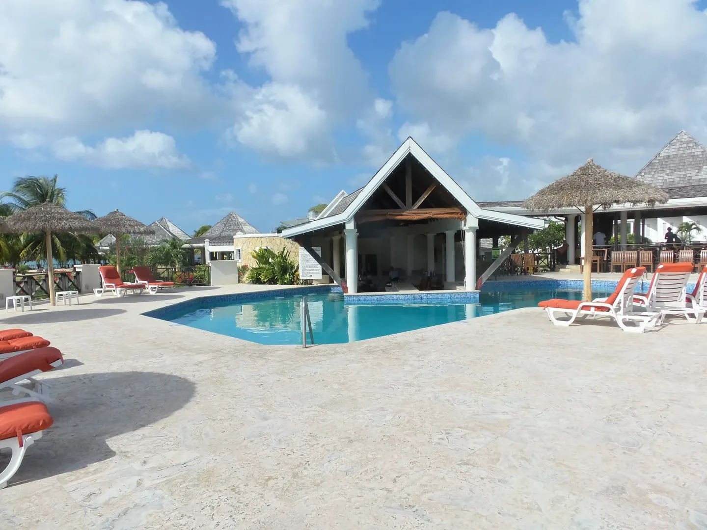 Main pool deck with loungers and thatched umbrellas at Coyaba Beach Resort.