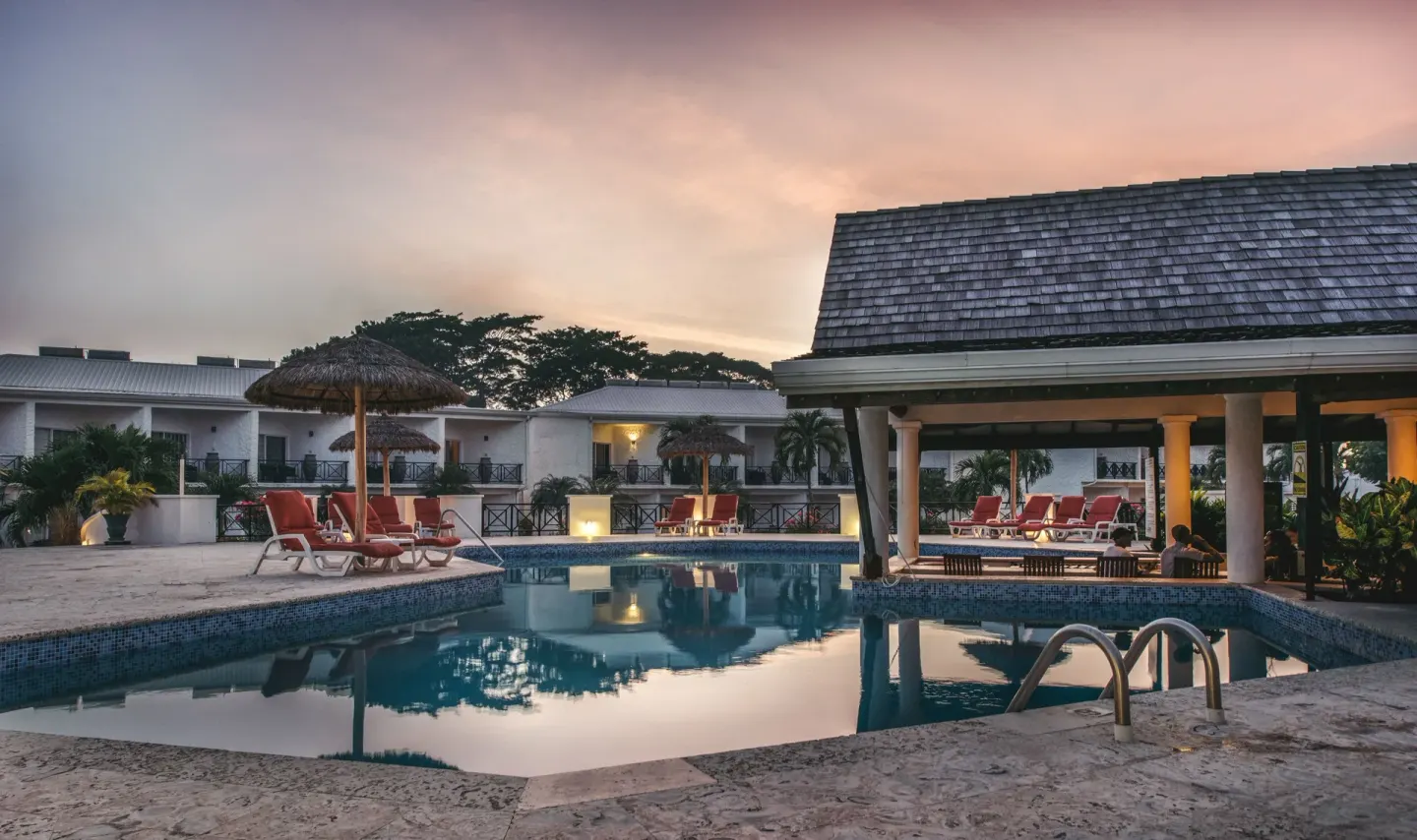 Pool deck with loungers and umbrellas at dusk at Coyaba Beach Resort.