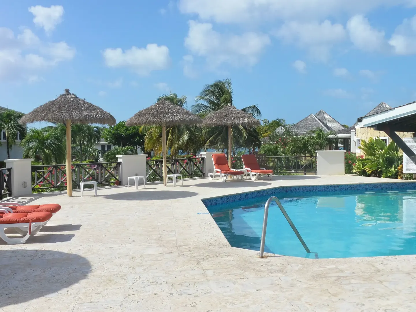 Poolside loungers under thatched umbrellas at Coyaba Beach Resort.