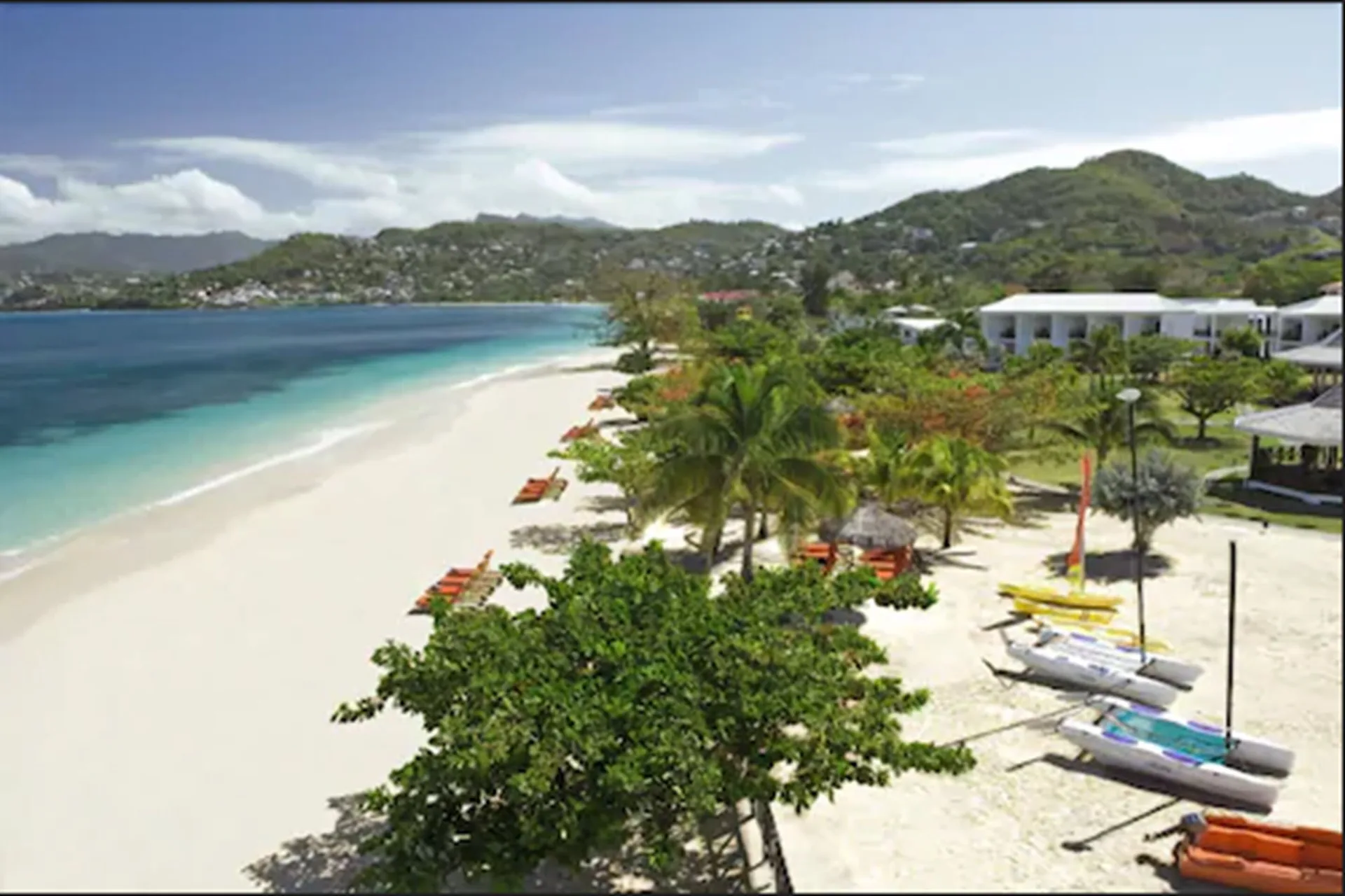 Wide beach view with sailboats and loungers at Coyaba Beach Resort.