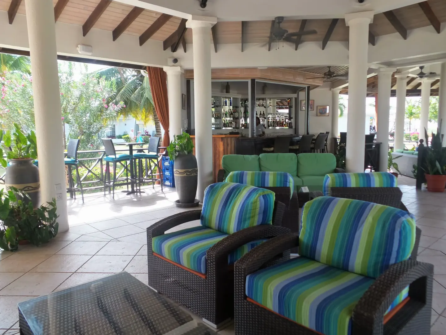 Open-air lounge with striped chairs and a bar at Coyaba Beach Resort.