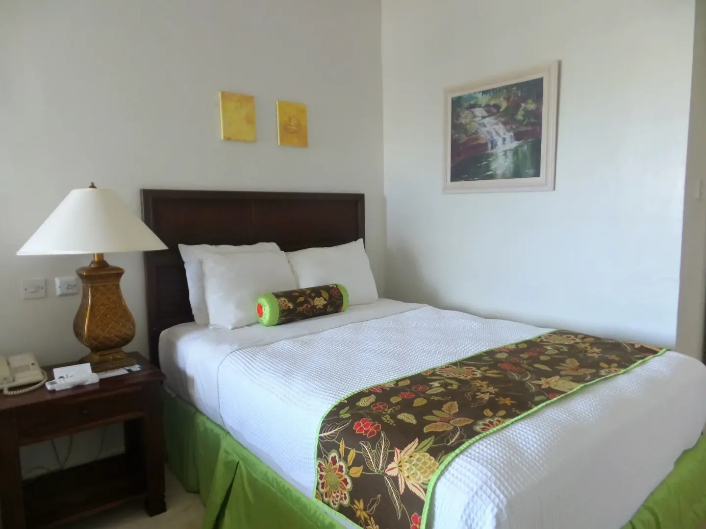 Superior Room king bed with bedside lamp and framed artwork at Coyaba Beach Resort.