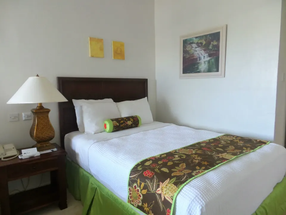 Superior Room king bed with bedside lamp and framed artwork at Coyaba Beach Resort.
