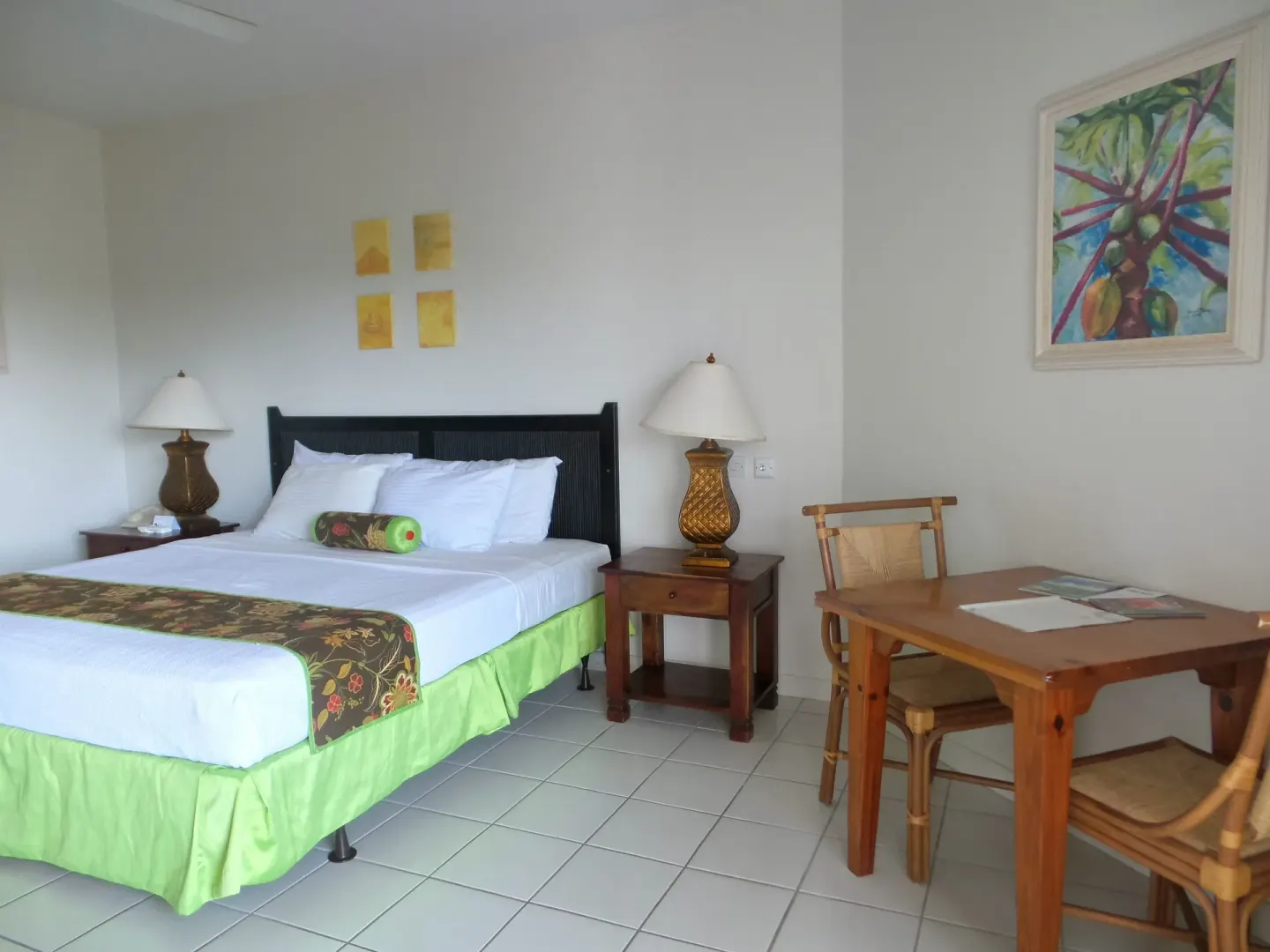 Superior Room king bed with dining table, chairs, and palm artwork at Coyaba Beach Resort.