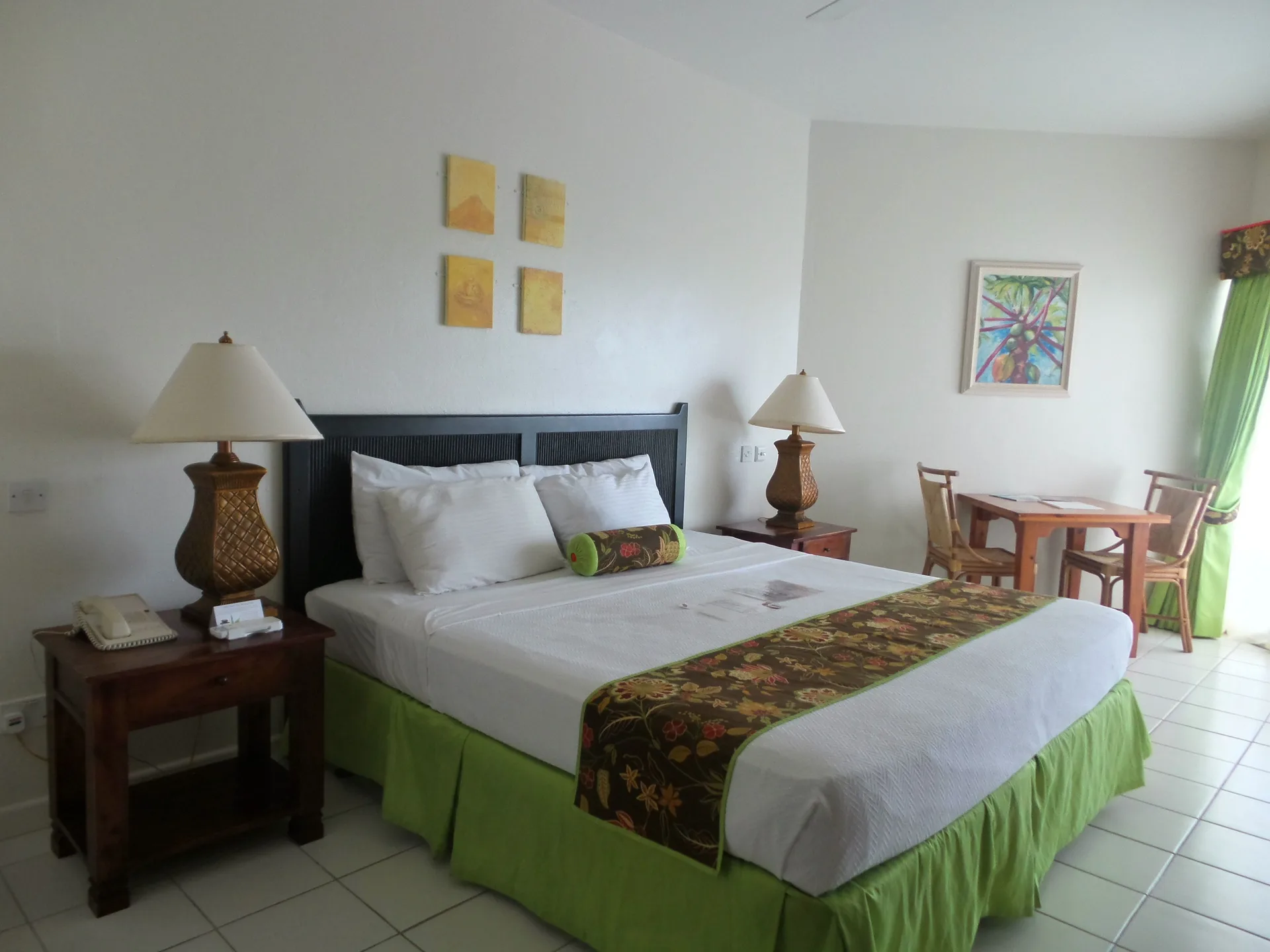 Superior Room king bed with seating area and green curtains at Coyaba Beach Resort.