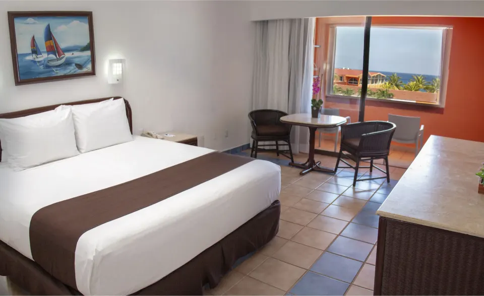 Guest room with king bed, seating area and ocean window at Cozumel Hotel & Resort.