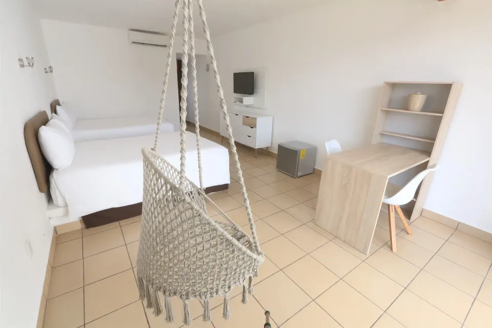 Hanging woven chair and twin beds in a guest room at Cozumel Hotel & Resort