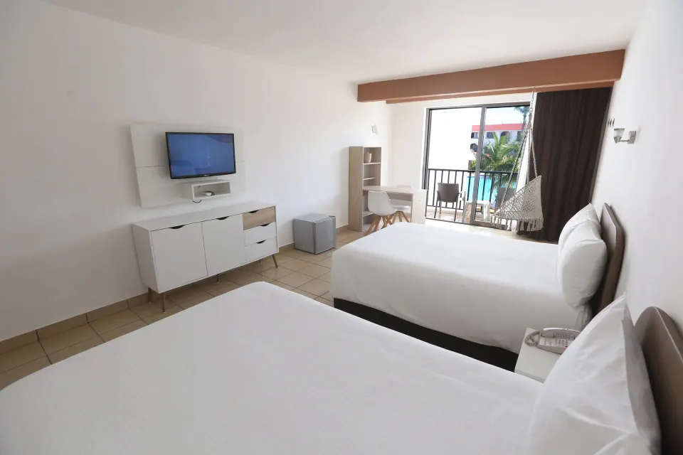 Two beds and a balcony overlooking the pool in a guest room at Cozumel Hotel & Resort