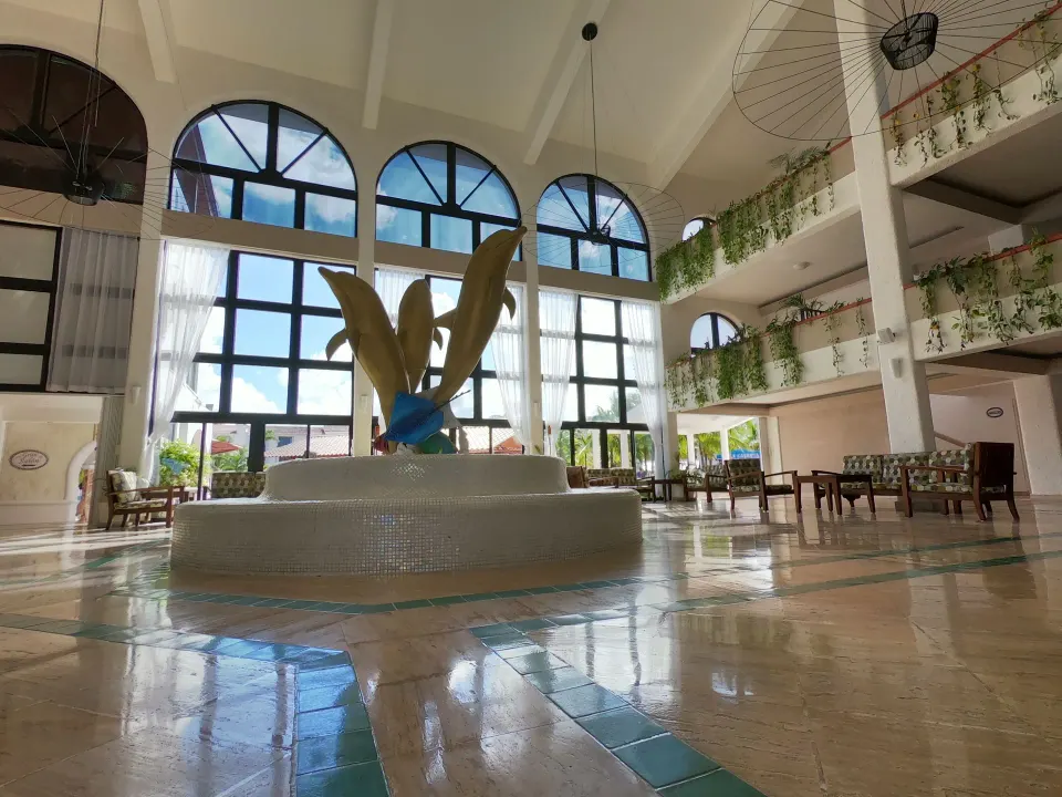Lobby interior with tall arched windows and central fountain sculpture at Cozumel Hotel & Resort