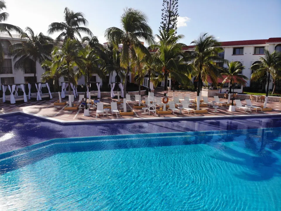 Pool deck with lounge chairs, cabanas and palm trees at Cozumel Hotel & Resort