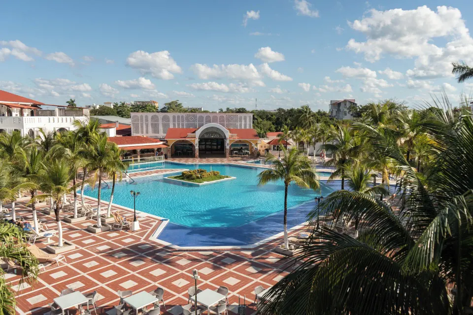Resort pool framed by palm trees and poolside seating at Cozumel Hotel & Resort